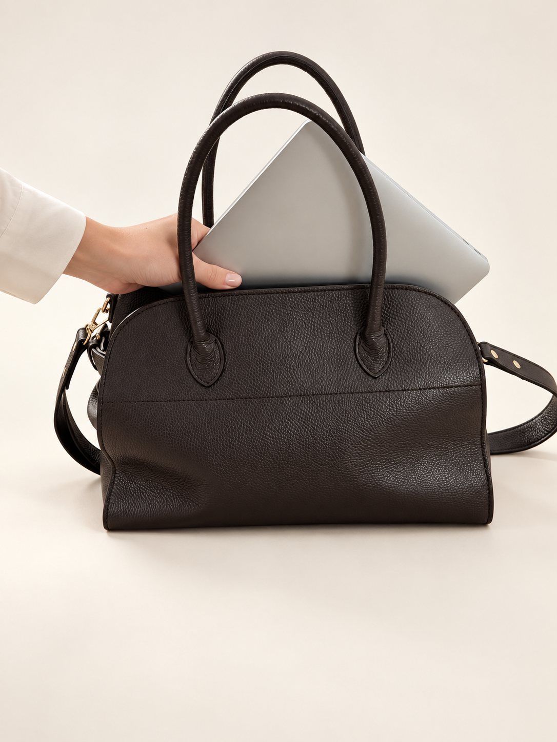 A 13-inch laptop slides into the LISHÉ Vira Moka Italian leather tote